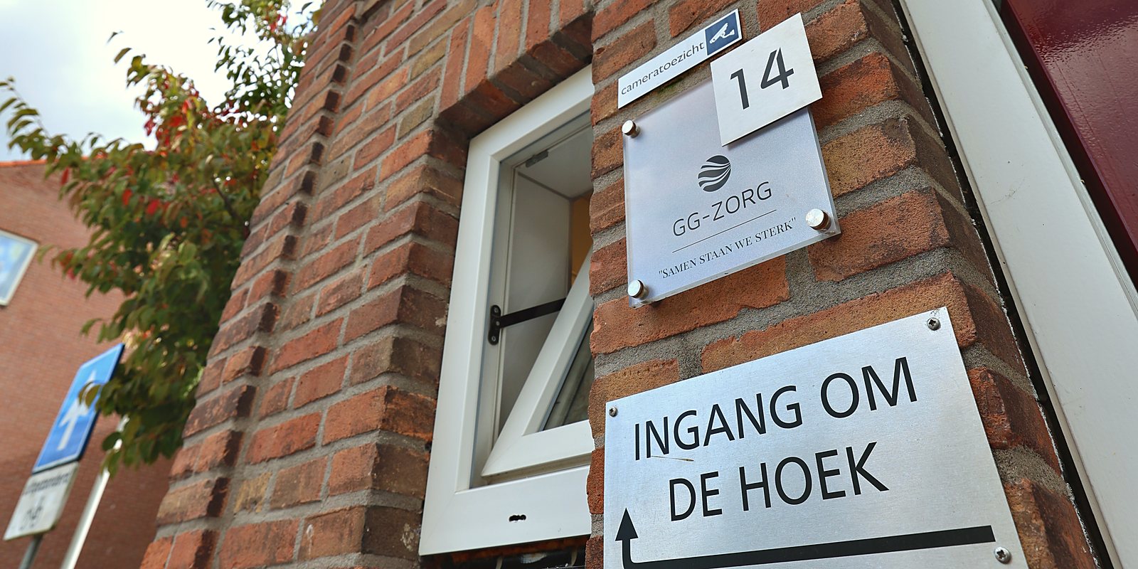 De hoek van Akkerwindestraat 14 met het naambord van GG-Zorg en het bordje 'Ingang om de hoek'